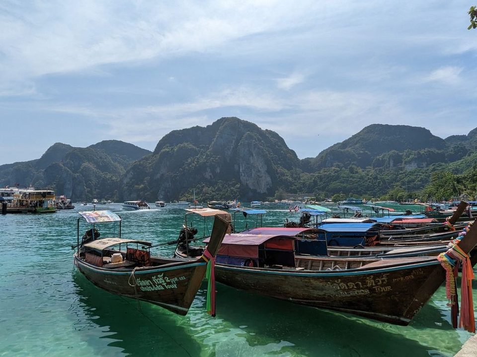Tayland'da kireçtaşı kayalıkların önünde bağlı longtail tekneleri